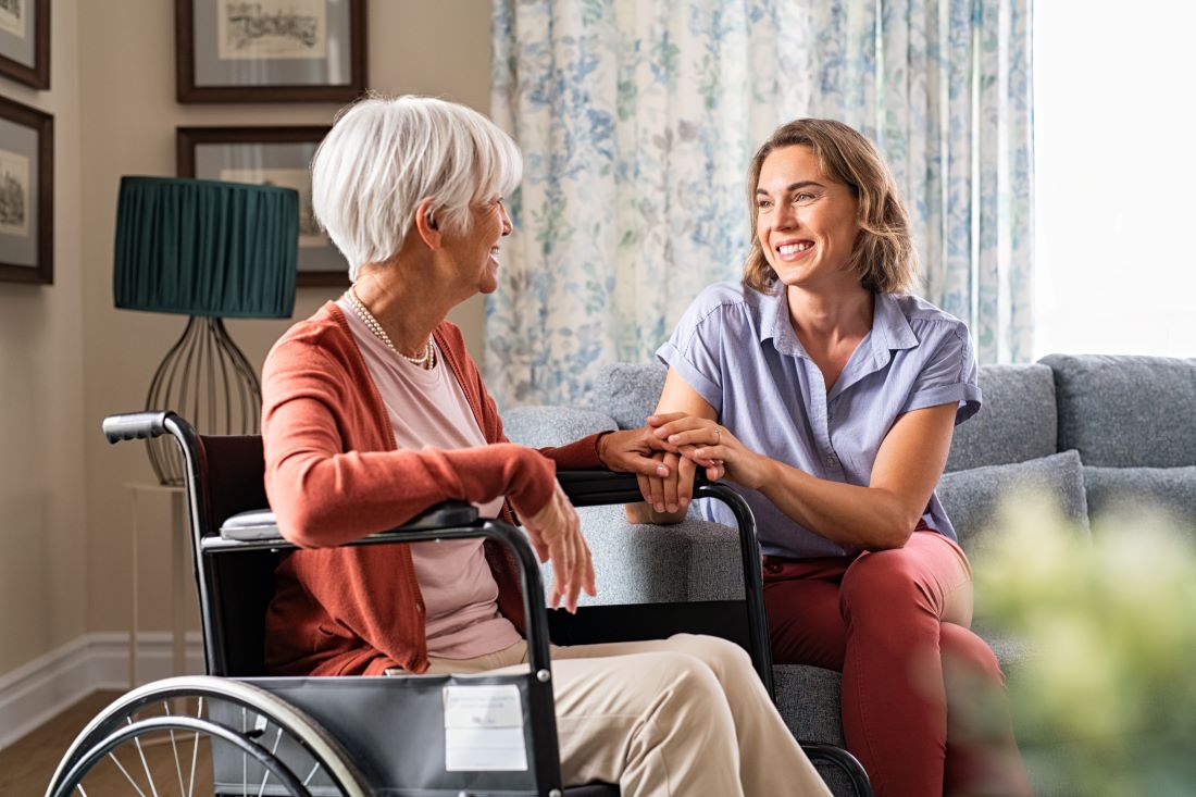 A wheelchair bound woman receives in-home respite care from a compassionate caregiver.