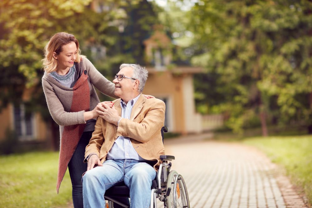 A caregiver helps a wheelchair-bound client get fresh air after returning home from a hospital stay.