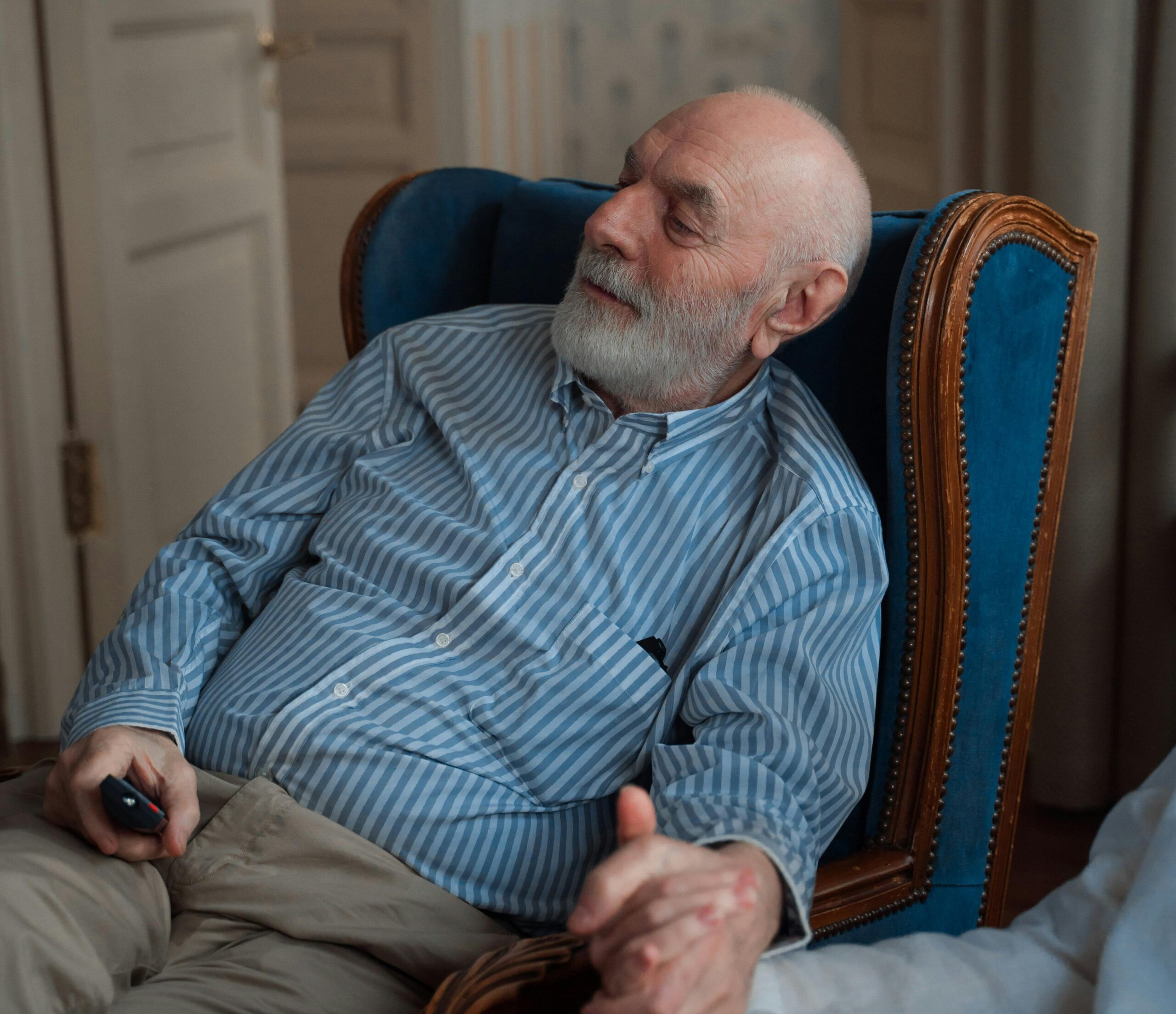 Elderly man watching TV at home, holding his wife's hand