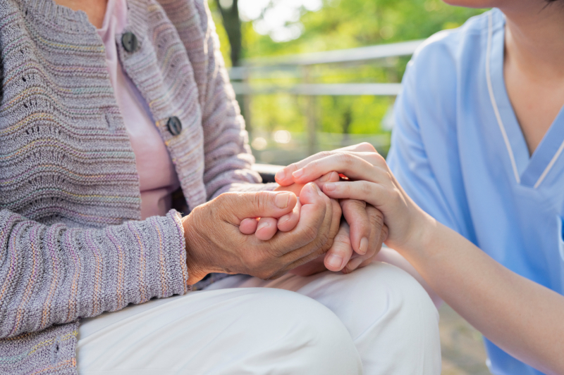 Woman and caregiver holding hands